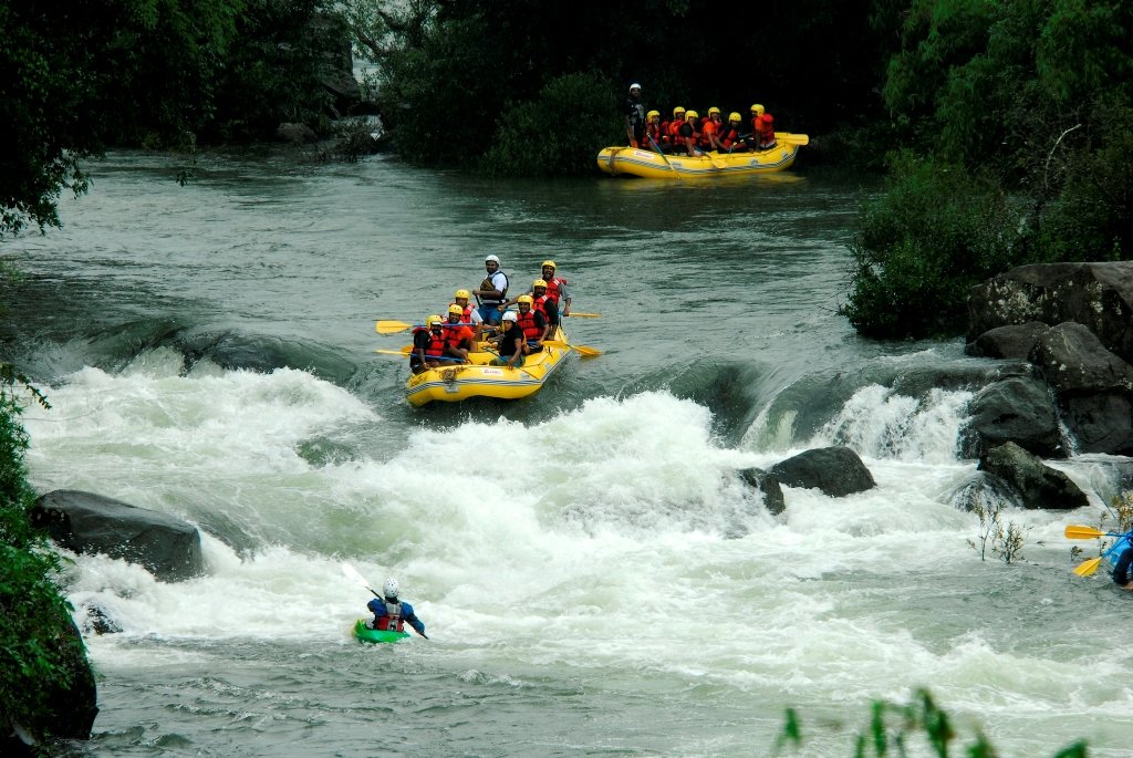 Adventure enthusiasts rafting through the thrilling white-water rapids of Coorg's Dubare River, surrounded by lush greenery.
