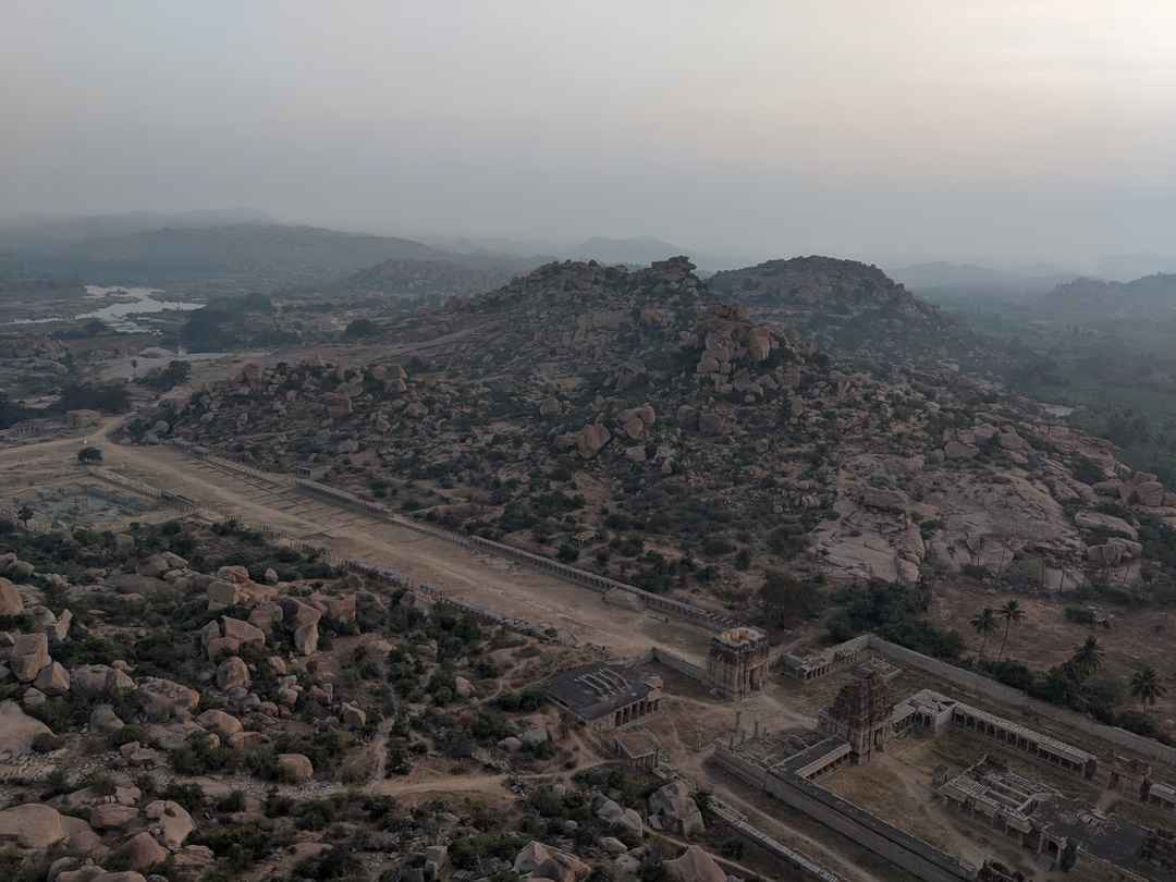 Aerial view of Hampi's ancient ruins and rocky landscape, with misty hills in the background.